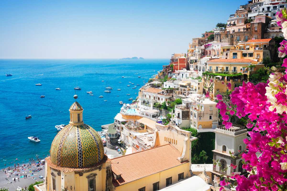 Scorcio della Spiaggia Grande di Amalfi vista dall’acqua, con ombrelloni colorati, bagnanti e il centro storico alle spalle