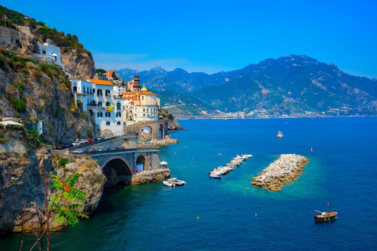 Passeggeri in attesa di traghetto al porto di Amalfi, scorcio sulla città, atmosfera vacanziera